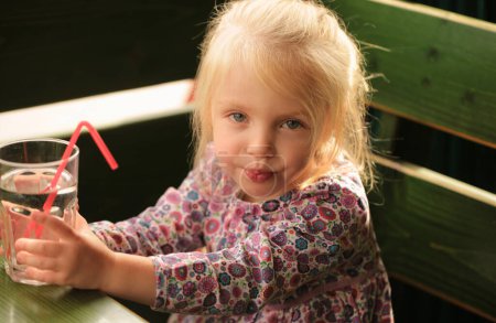 Foto de Retrato de una dulce y hermosa niña bebiendo un vaso de agua - Imagen libre de derechos