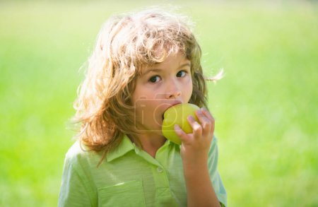 Téléchargez les photos : Jeune garçon de la campagne mange une pomme dans un verger de pommes ou une ferme - en image libre de droit