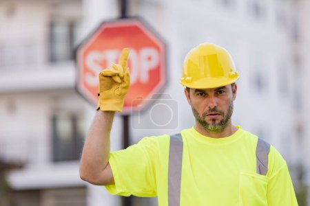 Foto de Hombre en uniforme de trabajador y hardhat con la mano abierta haciendo stop sign con expresión seria y segura, gesto de defensa. Ingeniero serio con señal de stop road - Imagen libre de derechos