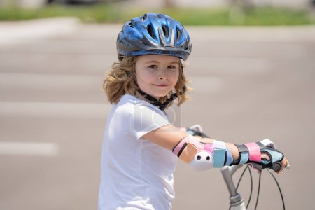 Téléchargez les photos : Enfant en vélo sportif dans le parc d'été. Enfant en casque de sécurité à vélo. Garçon à vélo dehors. Enfant en casque de sécurité à vélo. Le petit garçon apprend à faire du vélo. Enfant à vélo - en image libre de droit