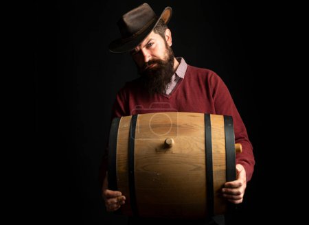 Photo for Man hold wooden barrel on black. Oktoberfest. Bearded brewer man. Serious man . Brewery concept. Beer for pub and bar. Oak barrels, keg. Man carries wooden barrel. Barrel with craft beer, whiskey - Royalty Free Image