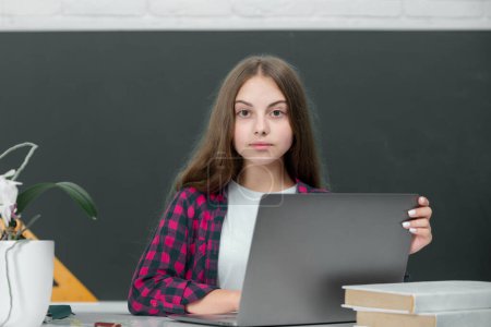 Foto de Adolescente estudiante de la escuela con portátil en la escuela. Estudiante adolescente trabajando en el ordenador portátil en el aula. Niña usando el ordenador portátil, estudiar en línea en el ordenador. Concepto de educación en el hogar. Lección escolar - Imagen libre de derechos