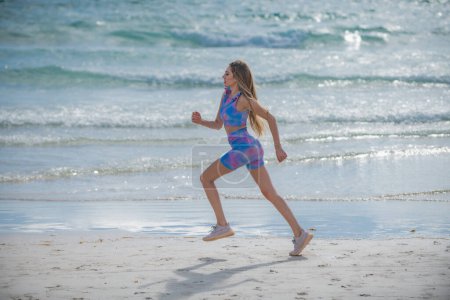 Téléchargez les photos : Femme qui court jogging sur la plage. Fit femme faisant de l'entraînement sur la plage d'été de sable de mer. Sport d'été. Fitness femme sport modèle jogging style de vie. La course. Fit girl courir sur la plage - en image libre de droit