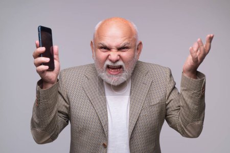 Téléchargez les photos : Homme âgé utilisant un smartphone, visage en colère. Mature homme parler sur téléphone mobile - en image libre de droit