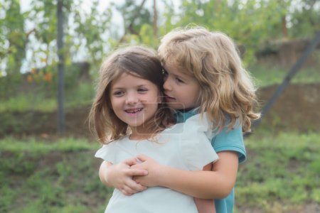 Téléchargez les photos : Deux petits enfants s'embrassent et s'embrassent dans le jardin d'été. Couple d'enfants amoureux. Amitié et enfance - en image libre de droit