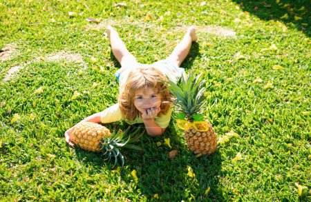 Photo for Portrait of little kid outdoors in summer. Smiling cute funny boy holding a pineapple - Royalty Free Image