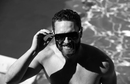 Foto de Resort piscina de verano. Un hombre guapo en vacaciones de verano. Hombre en gafas de sol relajante en la piscina - Imagen libre de derechos