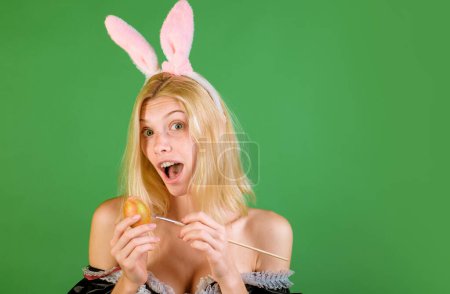Téléchargez les photos : Fille avec des oreilles de lapin tenant oeuf de Pâques, espace de copie. Drôle d'expression. Lapin lapin. Portrait de mode de belle femme sensuelle - en image libre de droit