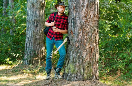Firewood as a renewable energy source. Lumberjack with axe on forest background. Deforestation is a major cause of land degradation and destabilization of natural ecosystems