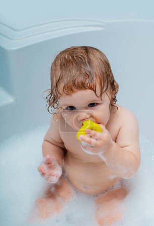 Todler in shower, funny infant in shower. Baby showering. Portrait of kid bathing in a bath with foam
