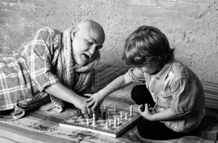 Téléchargez les photos : Enfant jouant aux échecs. Pièce d'échecs. Concept de grand-père et petit-fils - en image libre de droit