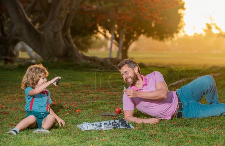 Téléchargez les photos : Père et fils jouant aux échecs dans un parc ensoleillé - en image libre de droit
