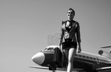 Stewardess. Journey and jet trip. Woman and commercial plane. Portrait of charming stewardess wearing in blue uniform. Stewardess and travel time. Business people and commercial jetliner