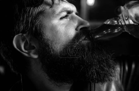 Foto de El hombre con barba sostiene brandy de vidrio. Un hombre sosteniendo un vaso de whisky. Bebiendo whisky. Degustación, degustación. Barbería. Afeitado. Retrato de hombre con barba - Imagen libre de derechos