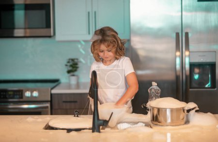 Photo for Child cleaning dishes with sponge. Cleaning supplies. Help clean-up. Housekeeping duties. Kid wash dishes. Little housekeeper. Child washing and wiping dishes in kitchen - Royalty Free Image