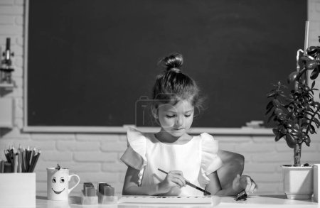 Foto de Cute little preschooler child girl drawing at school. Child girl painting on elementary school. Childhood learning, kids artistics skills - Imagen libre de derechos