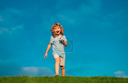 Téléchargez les photos : Garçon caucasien dans un parc courir et sourire. Joyeux gosse qui rit. L'émotion face à la joie enfant. Joyeux, drôle de printemps, jour d'été, à l'extérieur. Fond du ciel, bannière avec espace de copie - en image libre de droit