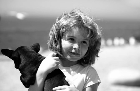 Foto de Happy child and puppy dog hugs her with tenderness smiling - Imagen libre de derechos
