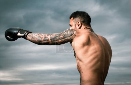 Foto de Boxeador atleta golpeando. Retrato de boxeador masculino. Hombre musculoso en guantes de boxeo al aire libre. Boxeador atlético. Golpe de boxeador - Imagen libre de derechos