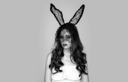 Foto de Retrato de mujer del deseo en orejas de conejo. El estudio disparó a una joven con orejas de conejo. Sexy morena hermosa mujer posando en máscara de conejo negro sobre fondo gris - Imagen libre de derechos