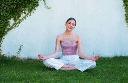 Téléchargez les photos : Méditation yoga femme dans le parc de printemps. Femme de yoga étirement avec pose étirement. Fit fitness athlète fille faisant des étirements sportifs. Entraînement extérieur sur herbe verte - en image libre de droit