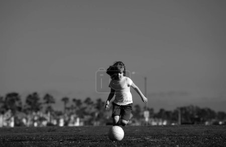 Téléchargez les photos : Little kid boy playing football in the field with soccer ball. Kids play soccer game. Concept of children sport - en image libre de droit