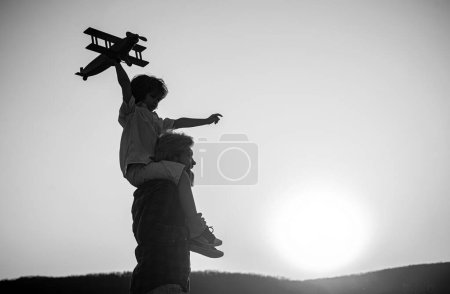 Photo for Sunset silhouette of Happy father and child son with airplane dreams of traveling. Father carrying his son on shoulders - Royalty Free Image