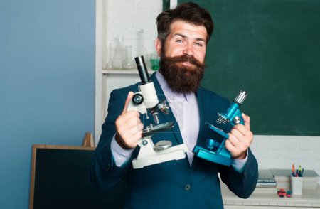 Photo for Portrait of teacher man with microscope, professor, tutor, mentor in school classroom - Royalty Free Image