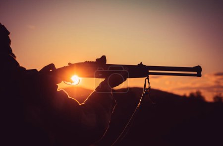 Calibers of hunting rifles. Rifle Hunter Silhouetted in Beautiful Sunset. Silhouette of the hunter. Pulled the trigger of the shotgun. Barrel of a gun
