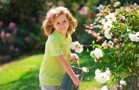 Foto de Plantas de riego para niños activas en el patio trasero. Niño ayudando a arents a cultivar hierbas y flores. Concepto ecológico - Imagen libre de derechos