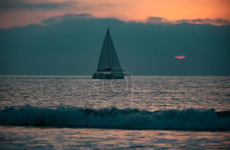 Photo for Panoramic view of sunset over ocean. Sailboat on the sea. Sailing boat floating on the blue ocean during sunrise with open main sail - Royalty Free Image