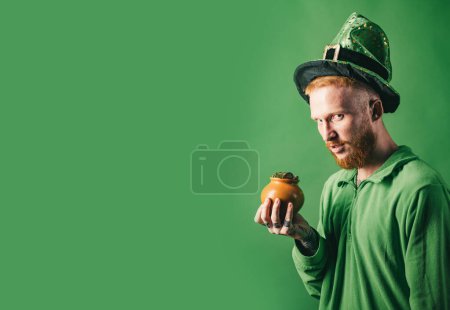Día de San Patricio. Patricks Day Pot of Gold y tréboles. Hombre de pelo rojo en la fiesta del duende de Saint Patricks Day sobre fondo verde. Copiar espacio
