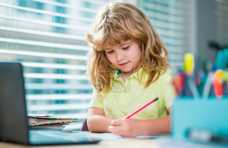 Téléchargez les photos : Child writing at school. Cute pupils writing at desk in classroom at the school. Cute boy doing homework, writing and painting. Preschooler boy with books at home - en image libre de droit