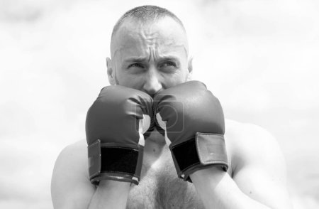 Téléchargez les photos : Closeup portrait of tough male boxer posing in boxing gloves. Professional fighter ready for boxing match. Sportsman muay thai boxer fighting - en image libre de droit