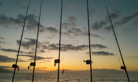 Canne à pêche et bobine sur la mer et le coucher du soleil ciel