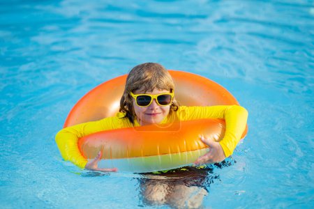 Photo for Child play in pool on inflatable ring. Kid with inflatable ring in swimming pool. Child water toys. Children play in tropical resort. Child in swiming pool. Kid floating in sea - Royalty Free Image