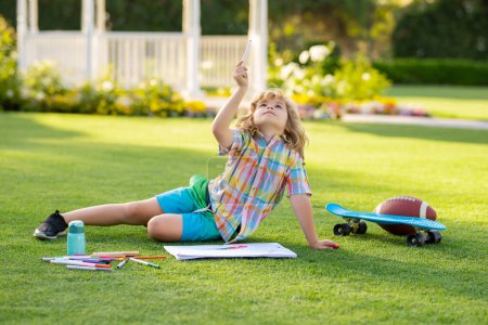 Photo for School kid drawing in summer park, painting art. Little painter draw pictures outdoor. Happy child playing outside. Drawing summer theme - Royalty Free Image