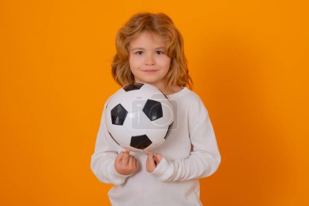 Kid holding soccer ball and smiling at camera, playing football, studio. Sport and leisure, soccer hobby for kids. Little boy holding soccer ball. Fan sport boy soccer player with football ball