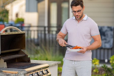 Chef préparant le barbecue. Cuire la viande masculine sur le barbecue grill. Filet de saumon homme cuisson sur barbecue pour le dîner de famille d'été à l'arrière de la maison