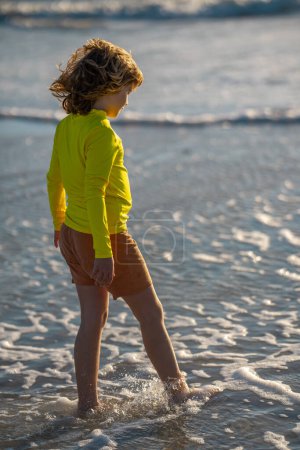 Téléchargez les photos : Happy child playing in the sea. Kid having fun outdoors. Summer vacation and healthy lifestyle concept. Cute kids having fun on beach in summer. Happy child playing in the sea. Summer vacation - en image libre de droit