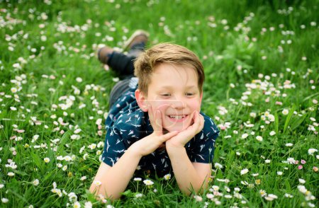 Muchacho de primavera en hierba. Lindo chico en flor de campo. Soñando niño
