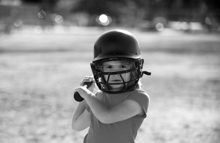 Little child baseball player focused ready to bat. Sporty kid players in helmet and baseball bat in action
