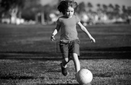 Foto de Niño jugador de fútbol pateando fútbol en el campo de deportes. Niños activos. Fútbol infantil. Fútbol infantil jugar fútbol en el parque - Imagen libre de derechos