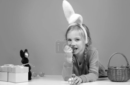 Téléchargez les photos : Enfant de Pâques. Fille drôle portant des oreilles de lapin et s'amuser avec des œufs de Pâques. Petite fille mignonne portant des oreilles de lapin le jour de Pâques - en image libre de droit