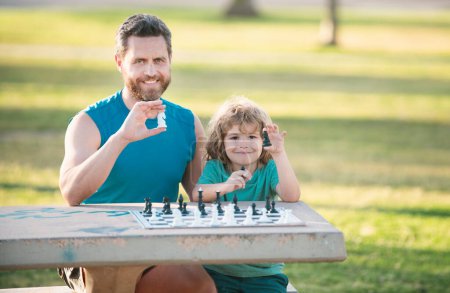 Téléchargez les photos : Père et fils jouant aux échecs passent du temps ensemble dans le parc. Gamin jouer aux échecs - en image libre de droit