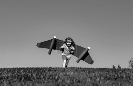 Photo for Kid with toy jetpack outdoor. Child playing in green spring field with cardboard wings. Spring travel and adventure. Kids success and leader, startup concept - Royalty Free Image