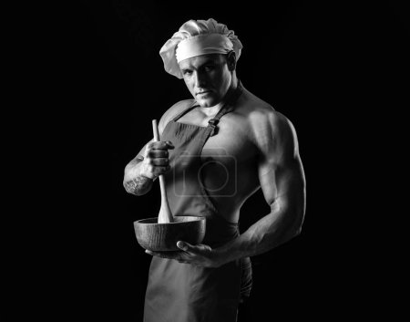 Foto de Cocinero sexy en delantal. Chef musculoso sobre fondo negro. Dieta deportiva - Imagen libre de derechos