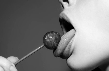 Foto de Labios sexuales con dulces, dulces sueños sexy. Mujer boca lame chupa chups, chupa lollipop - Imagen libre de derechos
