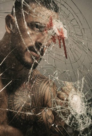 Brutal handsome macho focused on fight result. Want to fight right now. Fight concept. Man muscular body punching. Concentrated on target. Destroy obstacles. Handsome brutal man near broken glass.