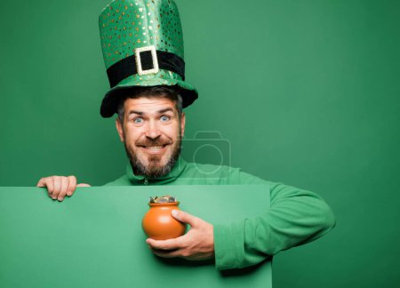 Grüner Patricks Hintergrund. Mann im Patricks-Anzug lächelt. Mann im Heiligen Patricks Day Kobold Party Hut Spaß auf grünem Hintergrund